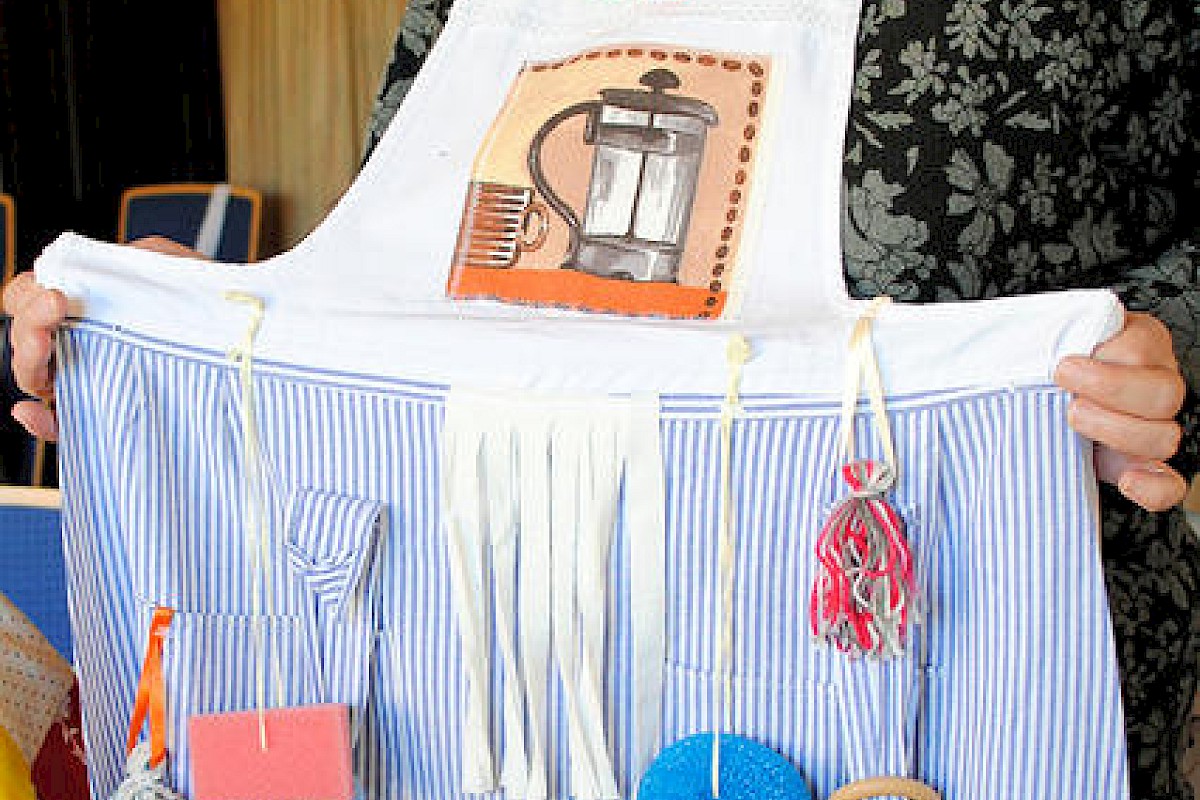 Elke Röscher, Initiatorin des Näh- und Kreativ-Cafés, präsentiert eine der ehrenamtlich gefertigten Nestel-Schürzen, die für Menschen mit Demenz geeignet ist. Foto: Rinke